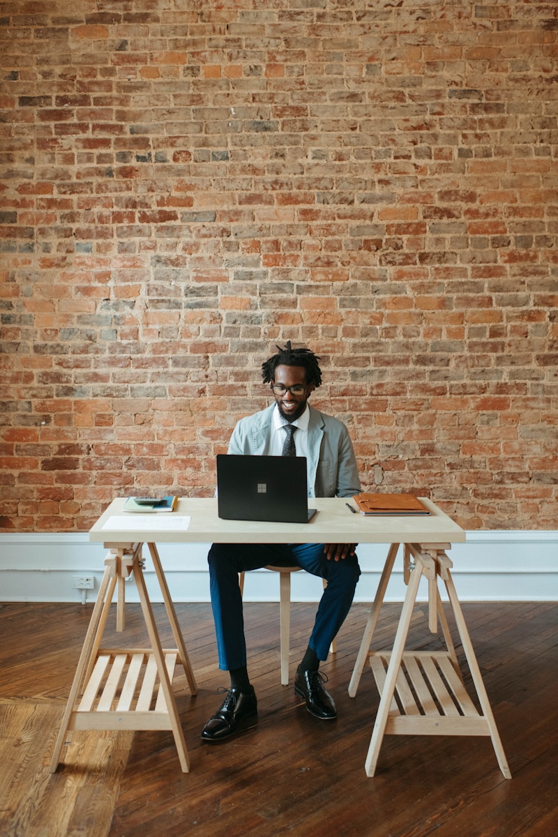 a man sitting at a table with a laptop on it reviewing general liability insurance